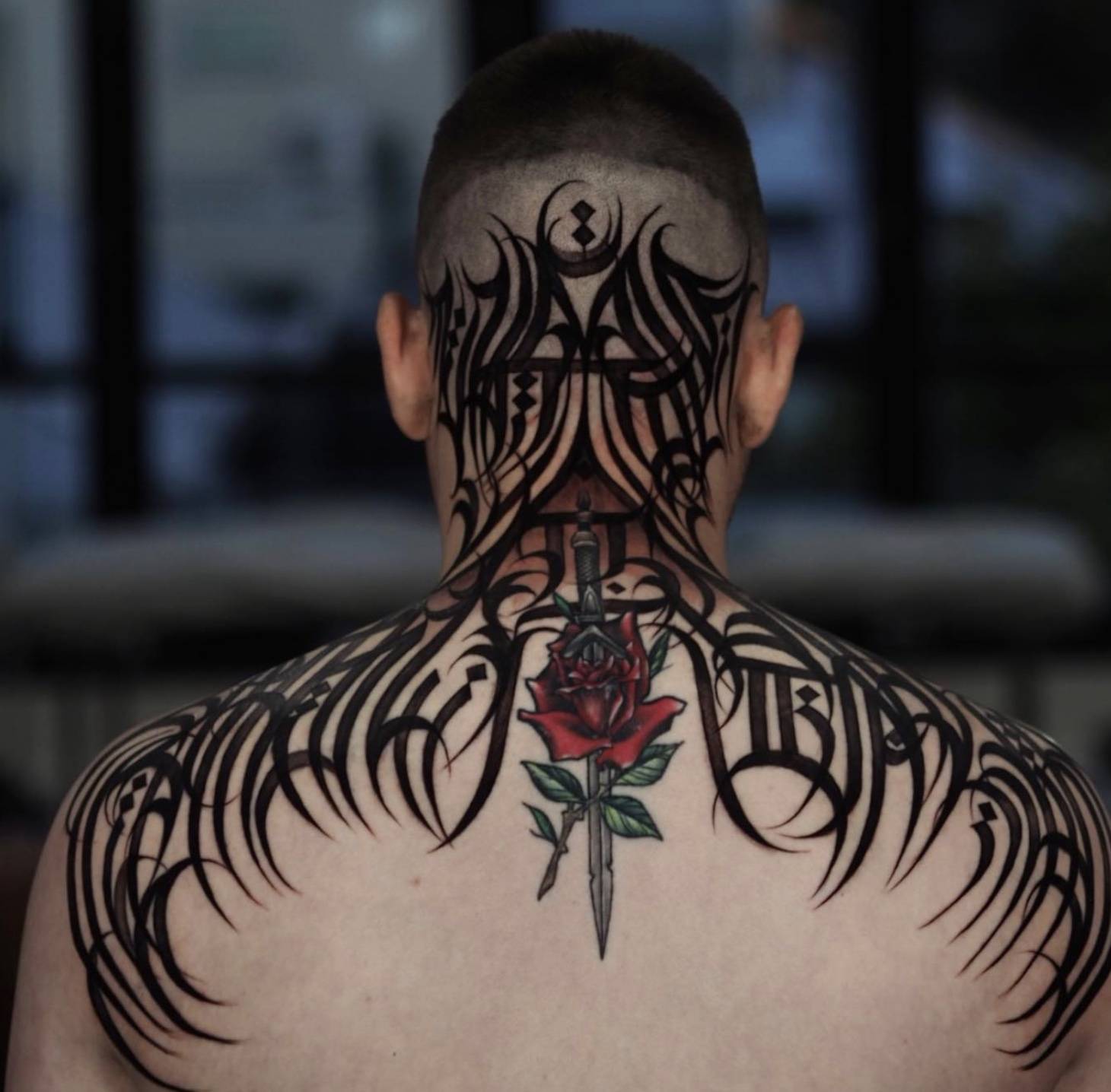 Back of head and neck featuring bold black abstract tribal-inspired tattoo design